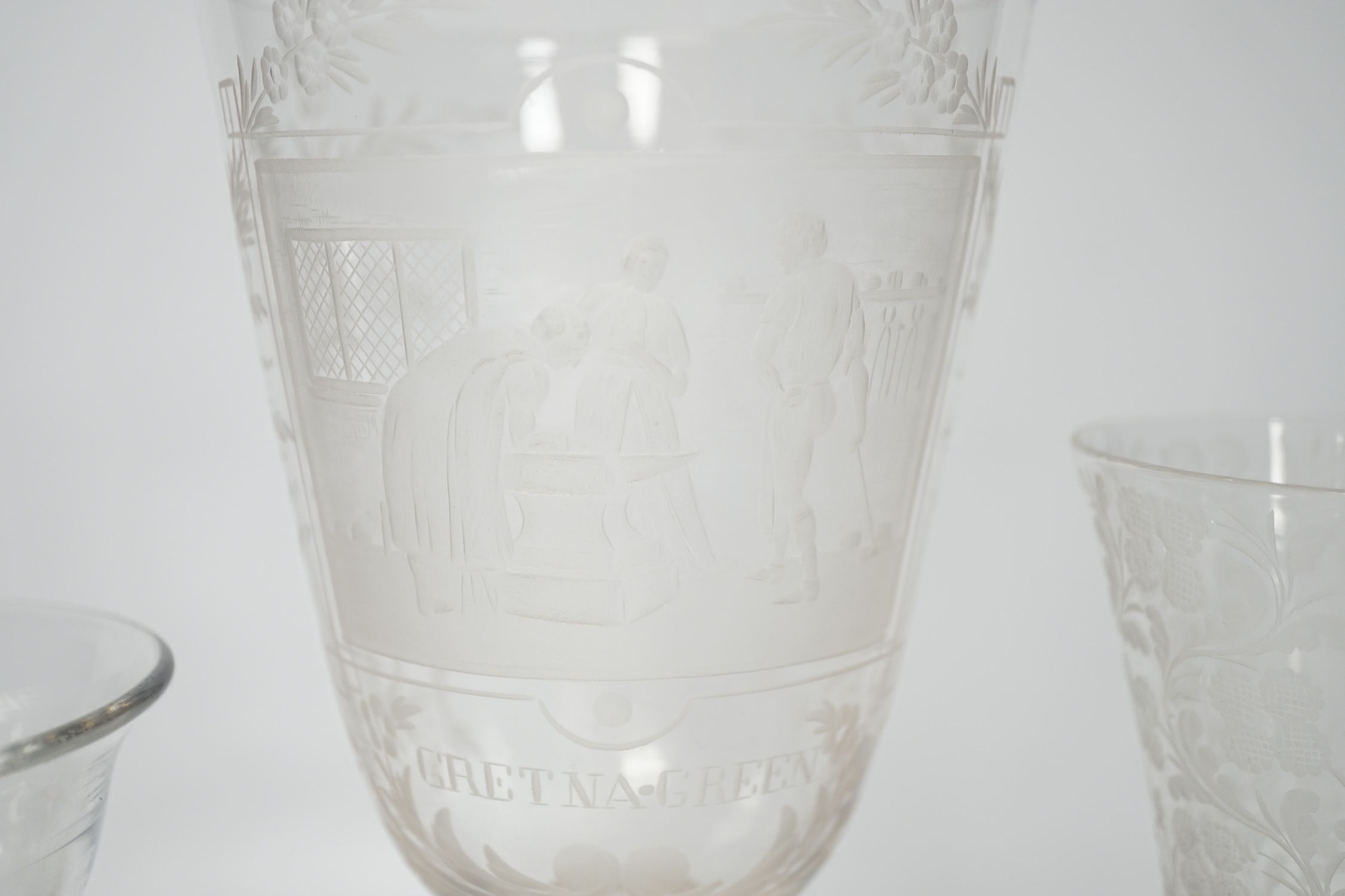 An 18th century sweetmeat glass, a 19th century large wheel engraved ‘Gretna Green’ goblet and a similar floral engraved glass, tallest 23cm. Condition good